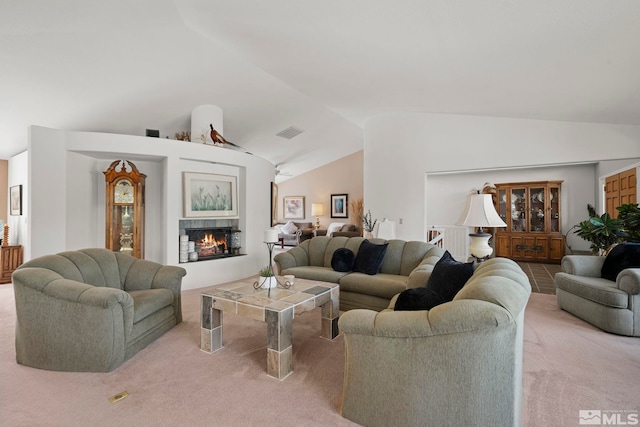 living room with a tiled fireplace, light carpet, and vaulted ceiling