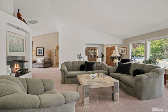 carpeted living room with a tiled fireplace and vaulted ceiling