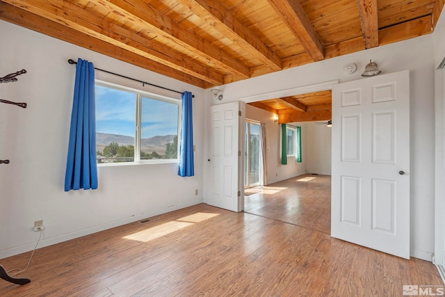 spare room featuring light wood-type flooring, wood ceiling, and beamed ceiling