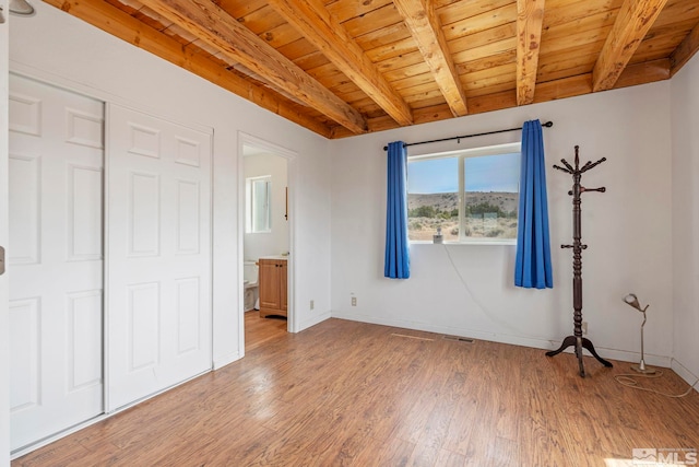 unfurnished bedroom with wooden ceiling, beamed ceiling, connected bathroom, and light hardwood / wood-style floors