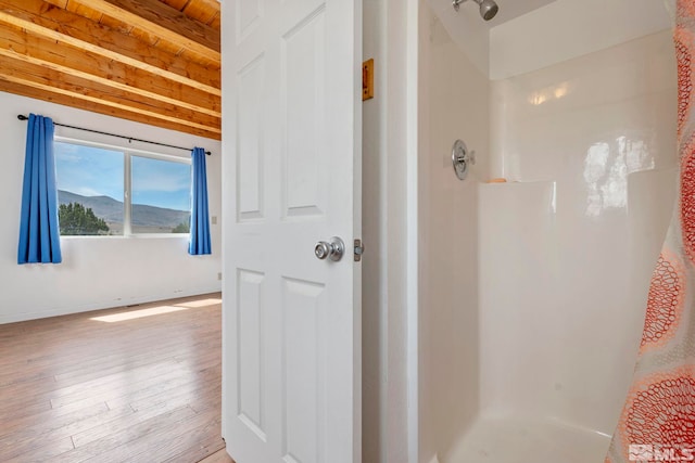 bathroom with a shower, wood-type flooring, and beam ceiling