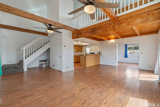 unfurnished living room featuring hardwood / wood-style floors, ceiling fan, and beam ceiling