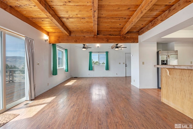 unfurnished living room with wood ceiling, a wealth of natural light, hardwood / wood-style flooring, and beam ceiling