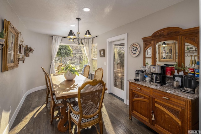 dining area featuring baseboards, a textured ceiling, an inviting chandelier, and dark wood finished floors