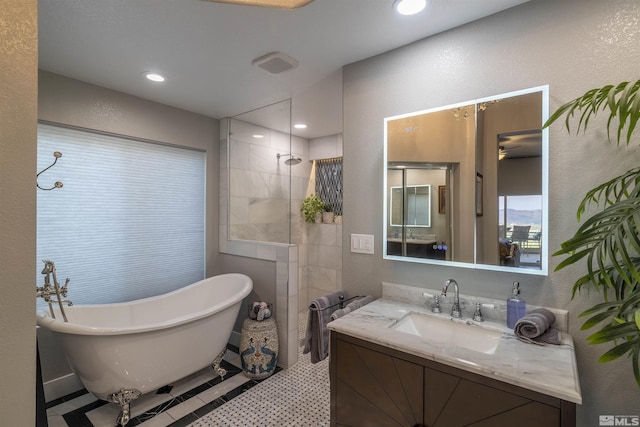 full bathroom featuring recessed lighting, a freestanding bath, walk in shower, vanity, and a textured wall