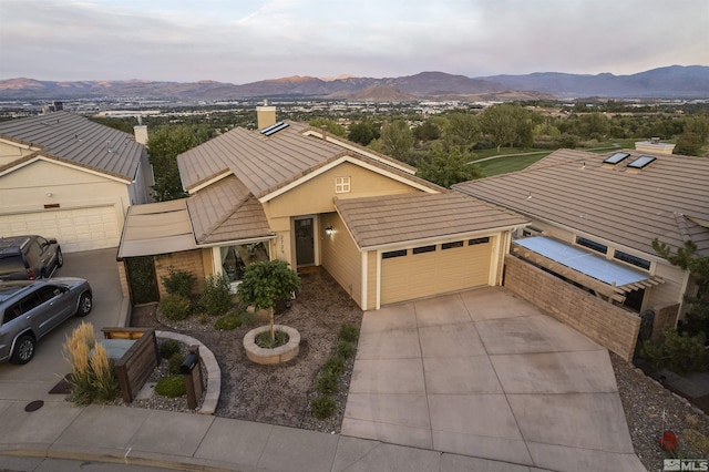 view of front of home with driveway, stucco siding, a garage, a tile roof, and a mountain view