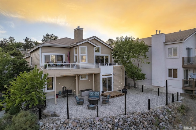 back of house at dusk featuring a patio and a chimney