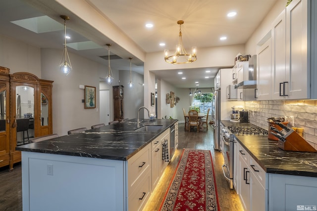 kitchen featuring dark wood finished floors, a sink, decorative backsplash, white cabinets, and appliances with stainless steel finishes