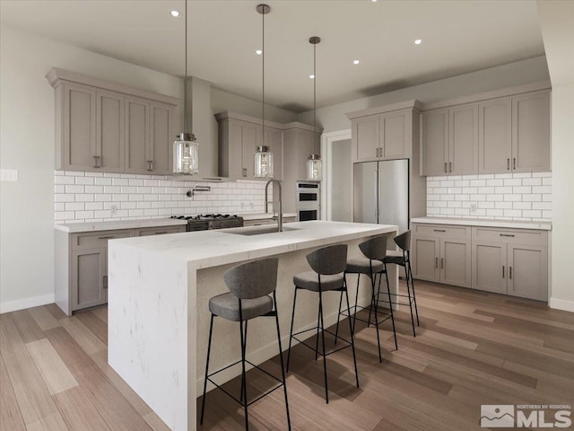 kitchen featuring a kitchen island with sink, a breakfast bar, sink, and light hardwood / wood-style floors