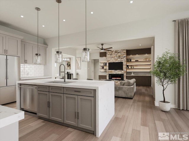 kitchen with gray cabinetry, a fireplace, light wood-type flooring, appliances with stainless steel finishes, and ceiling fan