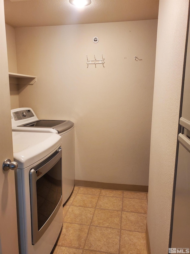 clothes washing area featuring a textured ceiling, light tile patterned flooring, and separate washer and dryer