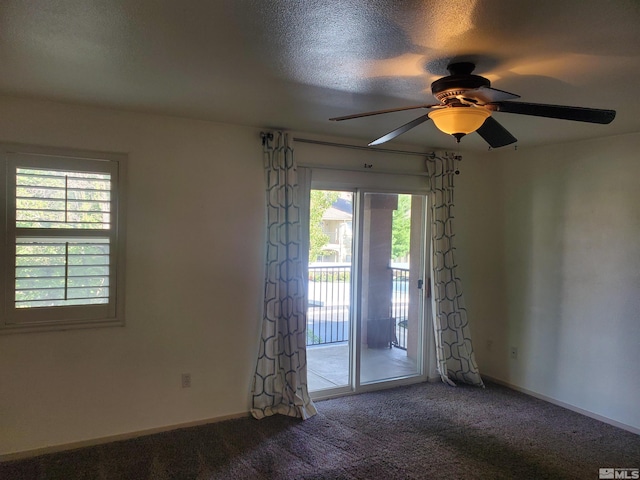 carpeted spare room featuring a textured ceiling, a healthy amount of sunlight, and ceiling fan