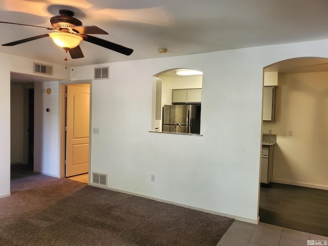 unfurnished living room with ceiling fan and carpet