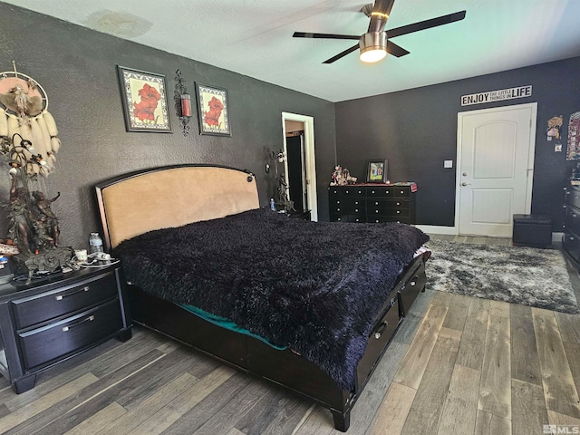 bedroom featuring dark wood-type flooring, a textured ceiling, and ceiling fan