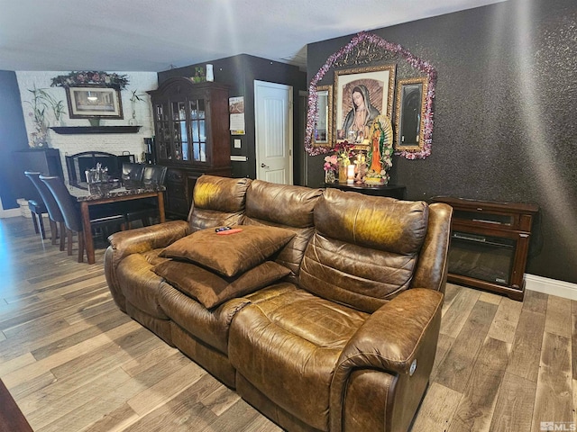 home theater featuring hardwood / wood-style floors and a brick fireplace