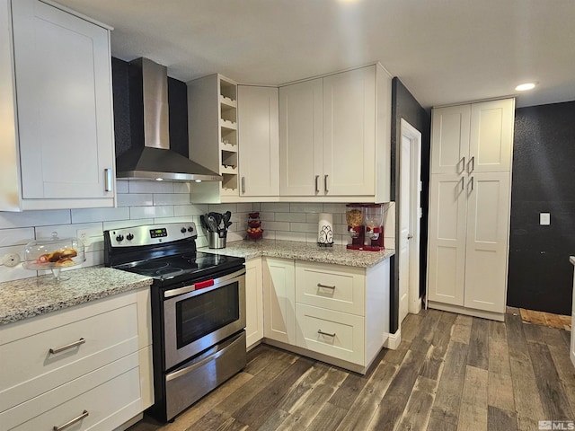 kitchen featuring white cabinets, light stone countertops, wall chimney range hood, dark wood-type flooring, and stainless steel range with electric cooktop