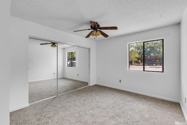 unfurnished bedroom with a textured ceiling, carpet, ceiling fan, and a closet