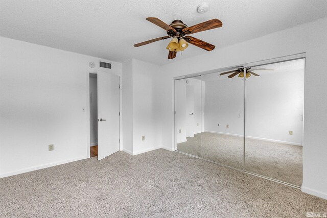 unfurnished bedroom featuring a textured ceiling, ceiling fan, a closet, and carpet floors