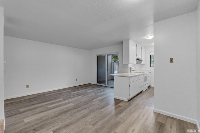 kitchen with light wood-type flooring, white cabinets, white range with electric stovetop, and a textured ceiling