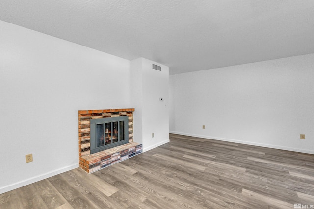 unfurnished living room with a textured ceiling, hardwood / wood-style flooring, and a fireplace