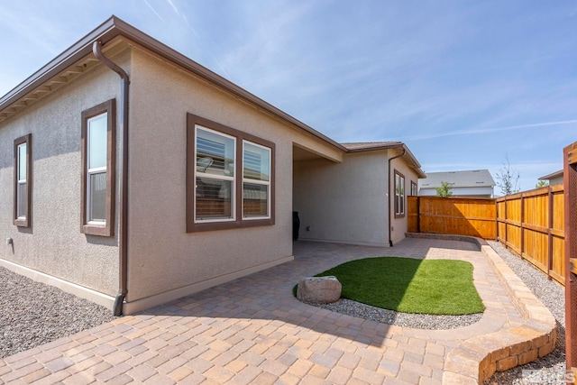 back of house with stucco siding, a patio, and fence