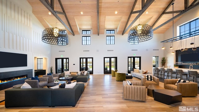 living area with wooden ceiling, beamed ceiling, light wood-style floors, and a warm lit fireplace