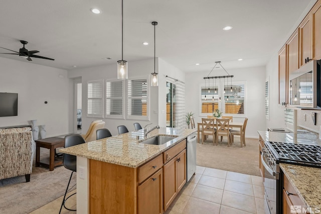 kitchen featuring a kitchen bar, a sink, open floor plan, appliances with stainless steel finishes, and light colored carpet