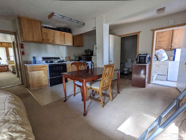 kitchen with separate washer and dryer, range with electric stovetop, and light colored carpet