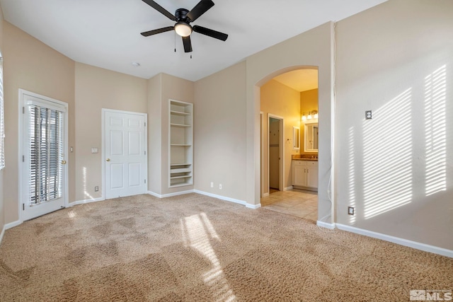 interior space with ceiling fan, access to outside, connected bathroom, and light carpet