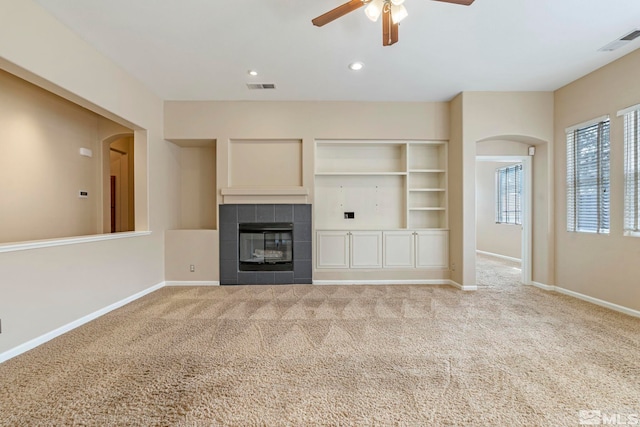 unfurnished living room featuring carpet, ceiling fan, and a tiled fireplace