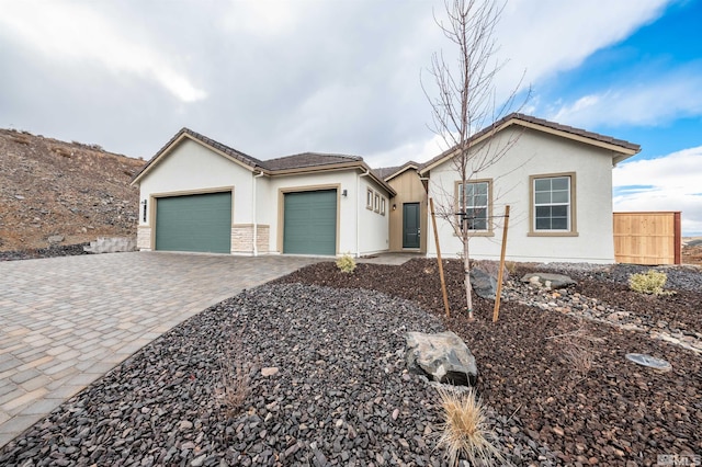 view of front of property with stucco siding, decorative driveway, and a garage