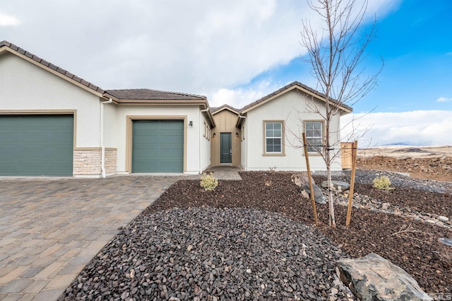 view of front of property with stucco siding, a tile roof, decorative driveway, and a garage