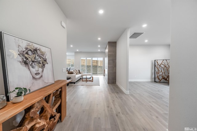 hallway with recessed lighting, visible vents, baseboards, and light wood finished floors