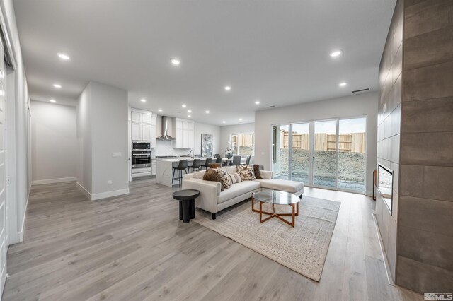 living area with recessed lighting, baseboards, and light wood-style flooring