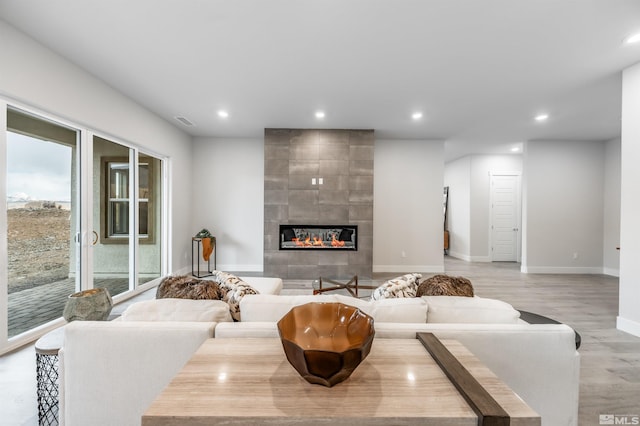 living room featuring recessed lighting, baseboards, light wood-style floors, and a fireplace