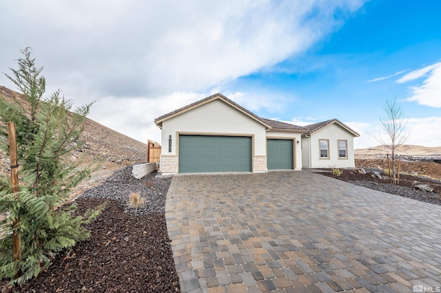 ranch-style house featuring stucco siding, an attached garage, and decorative driveway