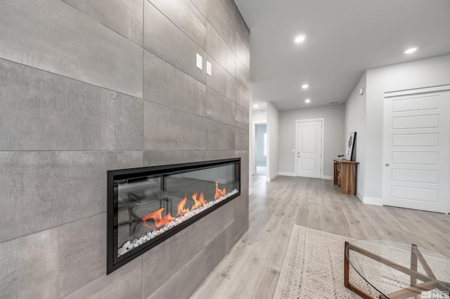 interior details with a tiled fireplace, recessed lighting, baseboards, and wood finished floors