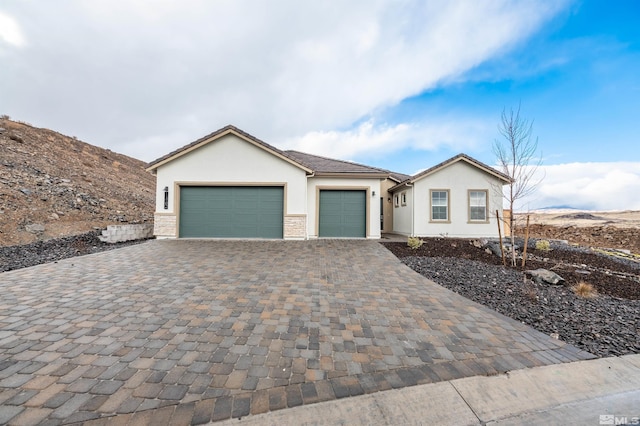 view of front of home featuring decorative driveway, an attached garage, and stucco siding