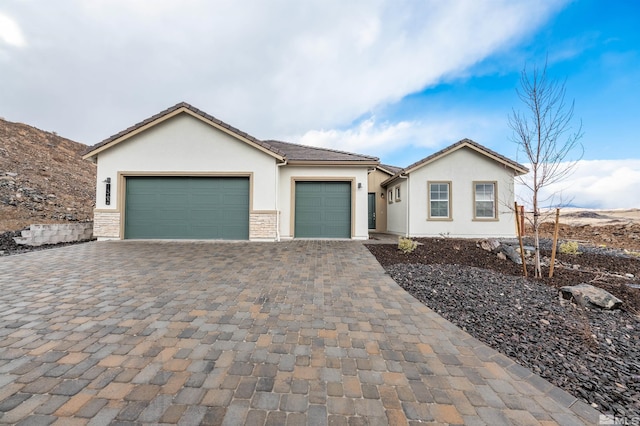 view of front facade with stucco siding, a tiled roof, decorative driveway, and a garage