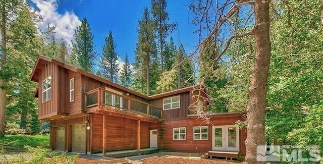 back of property with a garage and french doors