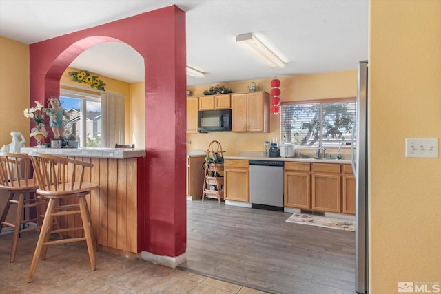 kitchen featuring a kitchen bar, stainless steel appliances, sink, and light hardwood / wood-style flooring