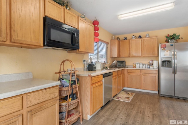 kitchen featuring wood-type flooring, light brown cabinets, appliances with stainless steel finishes, and kitchen peninsula