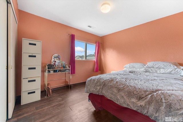 bedroom with dark hardwood / wood-style floors and a closet