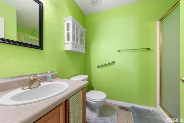 bathroom featuring tile patterned flooring, toilet, a shower with door, and vanity