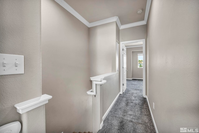 corridor with ornamental molding and dark colored carpet