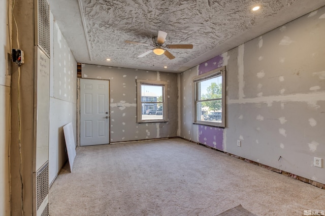 carpeted spare room featuring ceiling fan and a textured ceiling