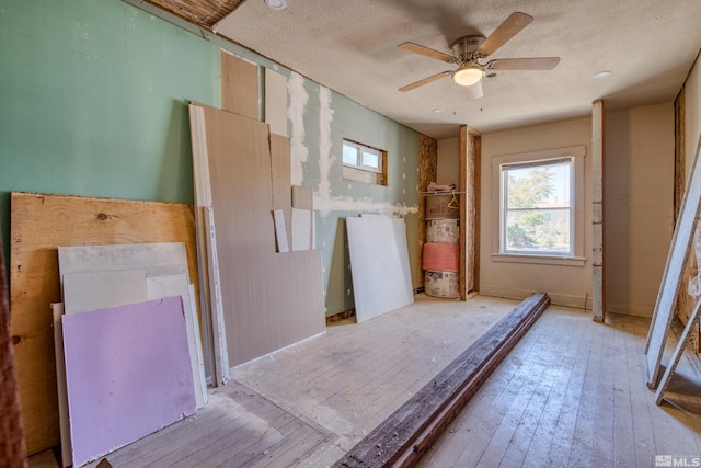 misc room with a textured ceiling, ceiling fan, and light hardwood / wood-style floors