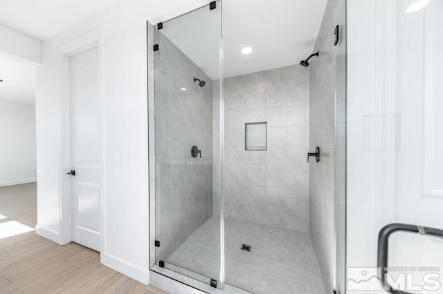 bathroom with hardwood / wood-style floors and an enclosed shower