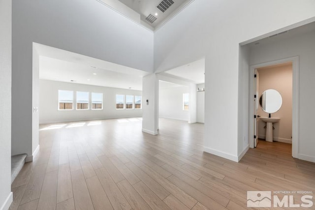 empty room with sink, a towering ceiling, and light hardwood / wood-style floors