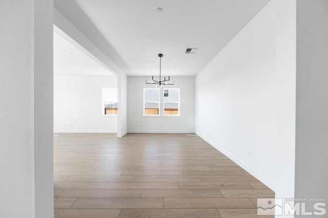 unfurnished dining area featuring light hardwood / wood-style floors and a chandelier